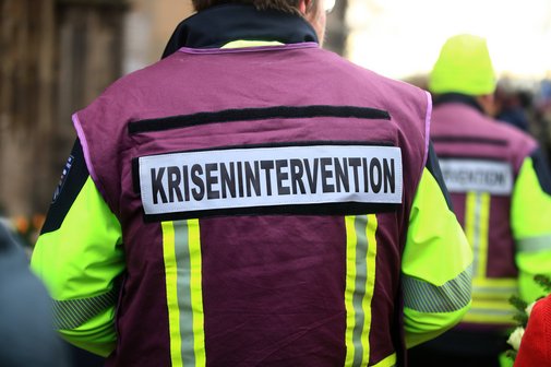 Ein Mann mit einer Einsatzweste, auf deren Rücken steht "Krisenintervention"