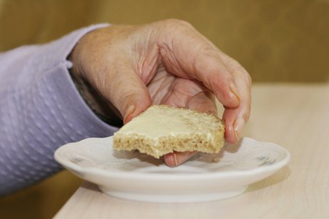 Essen in einem Altersheim Die Hand einer Frau in einem Altersheim greift nach einem Buttebrot