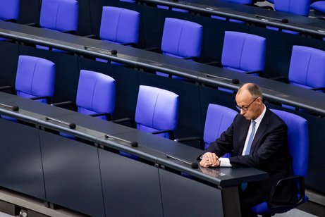 Bundeskanzler Friedrich Merz am Tag seiner Vereidigung im Bundestag, er sitzt allein im Plenum, schaut auf seine Hände.