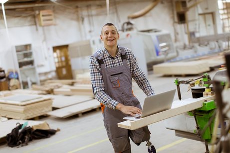 Behinderung am Arbeitsplatz Ein junger Mann mit einer Beinprothese an seinem Arbeitsplatz in einer Möbelfabrik.