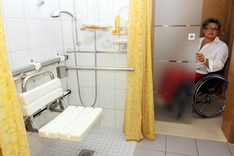 Frau im Rollstuhl an der Tür zu ihrem barrierefreien Badezimmer