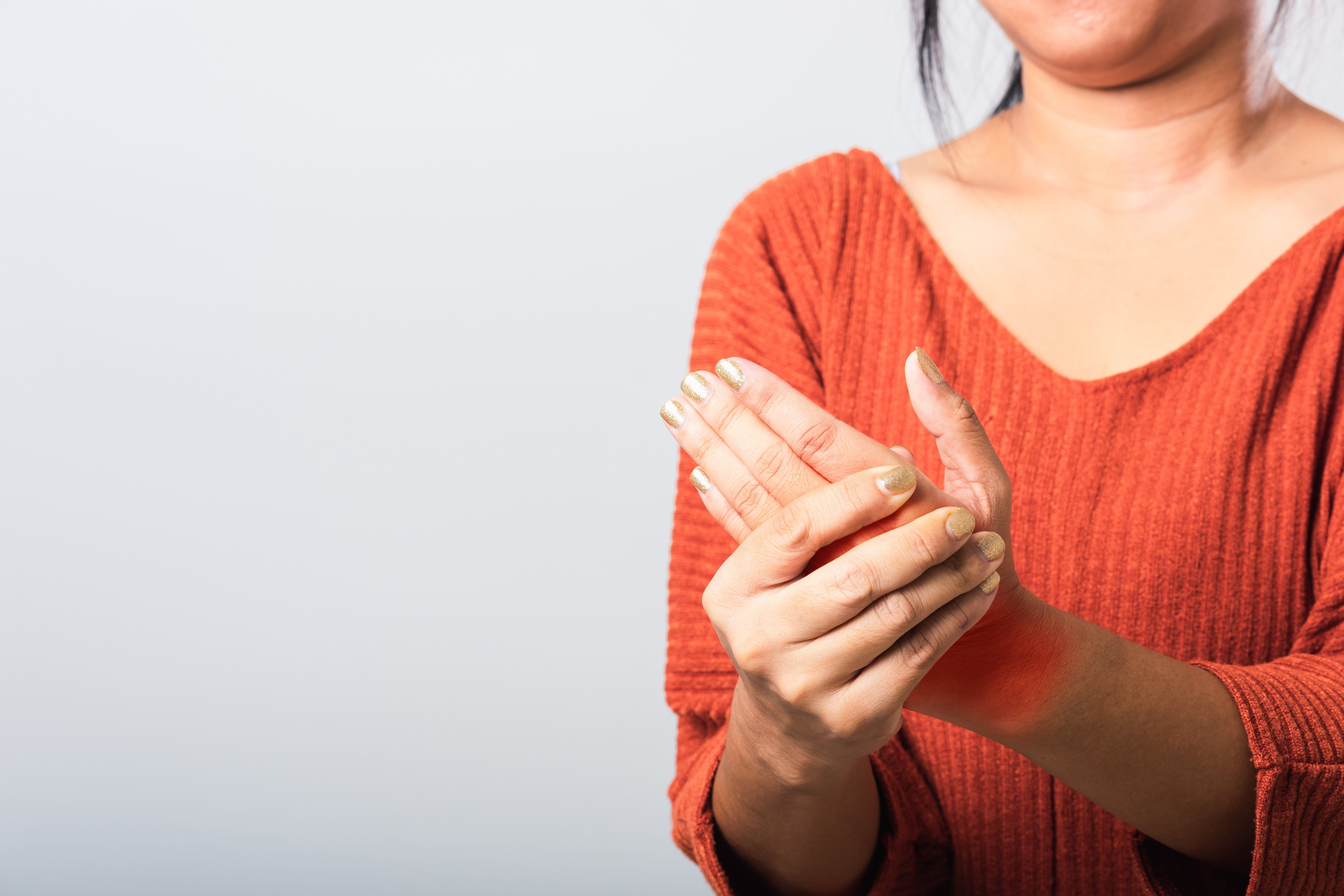 Eine Frau Hält sich ihre offenbar schmerzende Hand.