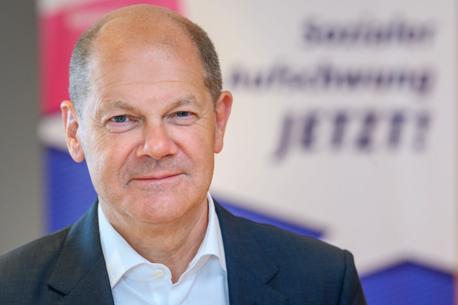 Das Portraitfoto zeigt Olaf Scholz vor dem Hintergrund der VdK-Kampagne "Sozialer Aufschwung jetzt!"