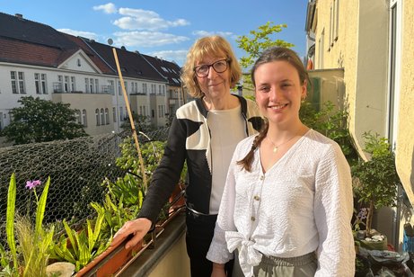  Cornelia Stauß und Beate Meißner stehen nebeneinander auf dem begrünten Balkon der Berliner Wohnung.