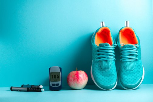 Utensilien bei Diabetikes, daneben liegt ein Apfel und Schuhe.