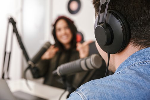 Ein Podcast mit einer Frau und einem Mann wird in einem Tonstudio aufgenommen.