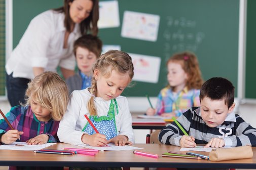 Kinder einer Schulklasse bei Malen unter Anleitung einer Lehrerin.