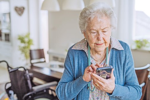 Eine &auml;ltere Frau stellt mit dem Smartphone einen Antrag auf Wohngeld.