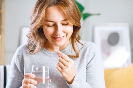 Umdenken - Wirkung von Arzneimitteln Glückliche junge Frau nimmt Vitamine.