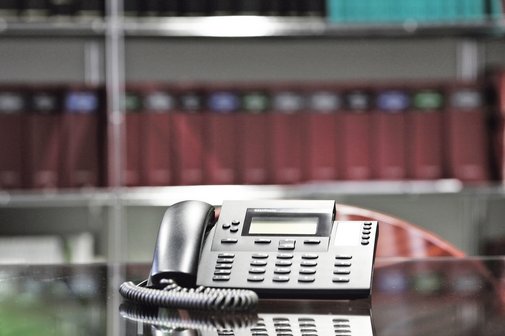 Ein Beratungszimmer mit Telefonapparat und Gesetzesbüchern in einem Regal.
