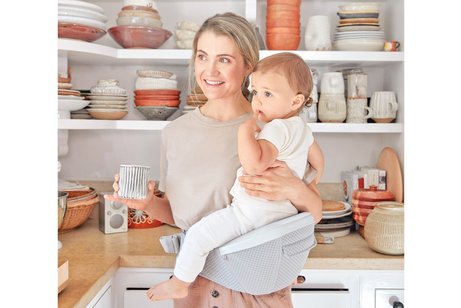 Eine Frau mit Baby in einer Hüftsitztrage.