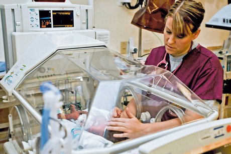 Das Bild zeigt eine Krankenschwester am Brutkasten bei der Frühgeborenenpflege.