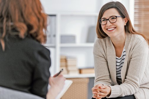 Steuertipp - Kosten für Psychotherapie absetzen Eine glückliche Frau während erfolgreicher Psychotherapie mit Therapeutin in der Klinik.