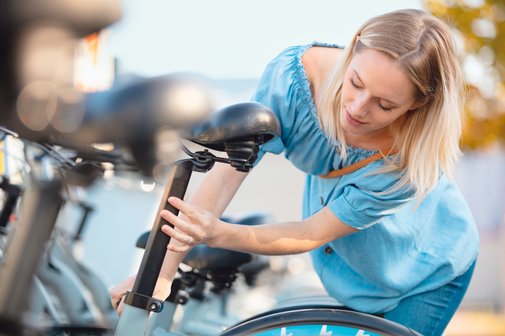 Eine Radfahrerin stellt den Sattel am Fahrrad ein.