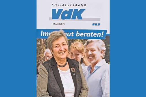 Karin Grudinzinski, abgebildet vor einem Plakat mit dem Schriftzug: VdK immer gut beraten.