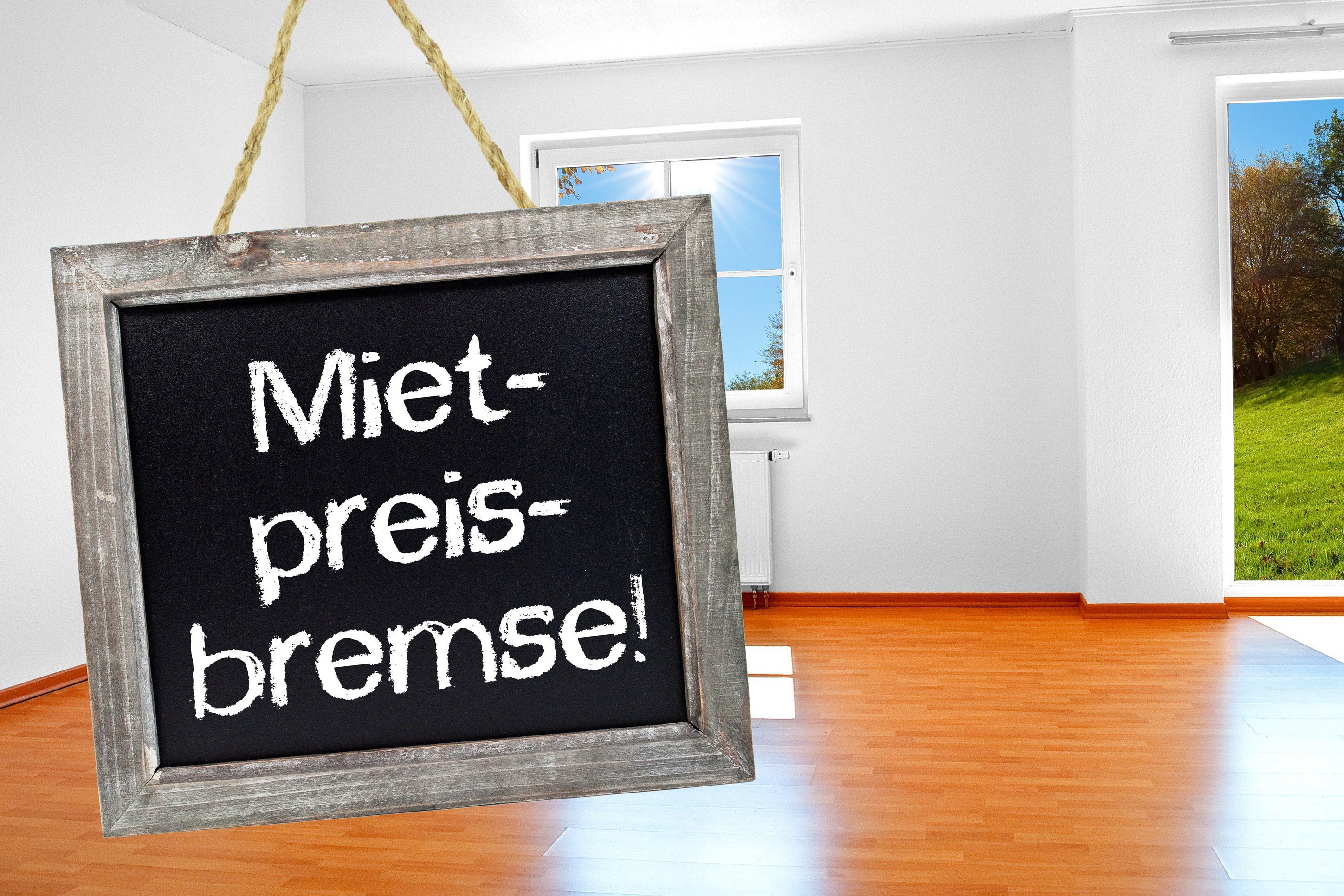 Kreidetafel mit Mietpreisbremse, platziert in einer leeren Wohnung.