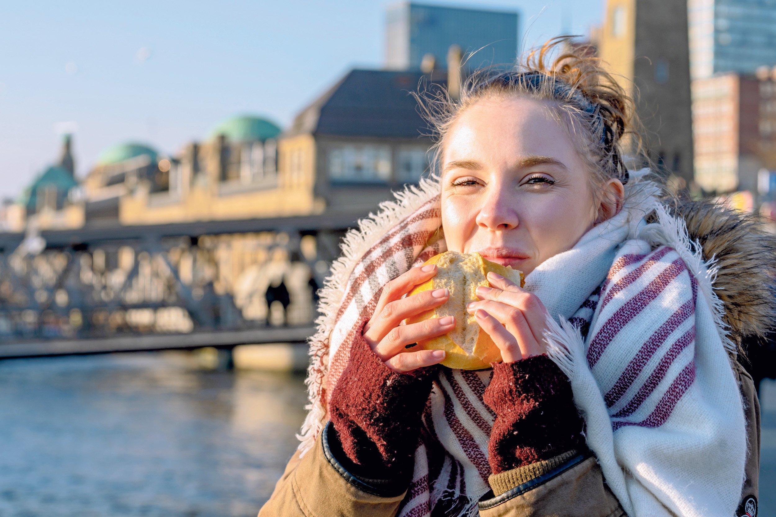 Eine junge Frau isst unterwegs einen Snack.