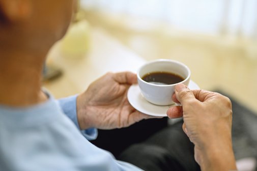 Eine Person hält eine Tasse Kaffee in den Händen.