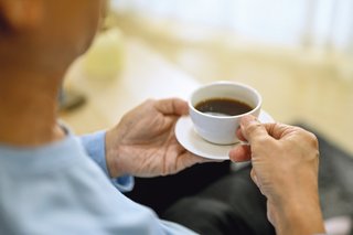 Eine Person hält eine Tasse Kaffee in den Händen.