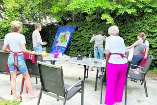 Das Bild zeigt junge Menschen mit Demenzerkrankung beim Malen in einem Garten.