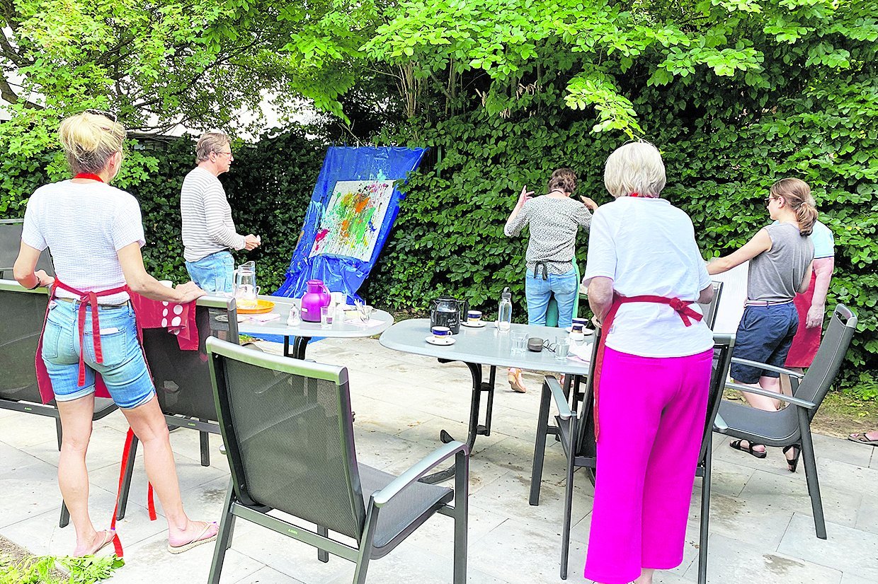 Das Bild zeigt junge Menschen mit Demenzerkrankung beim Malen in einem Garten.