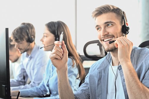 Portr&auml;t eines Callcenter-Teams mit gut gelaunten Kundendienstmitarbeitern bei der Arbeit.