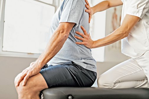 Ein Senior wird von einer Rehabilitationsphysiotherapeutin behandelt. 