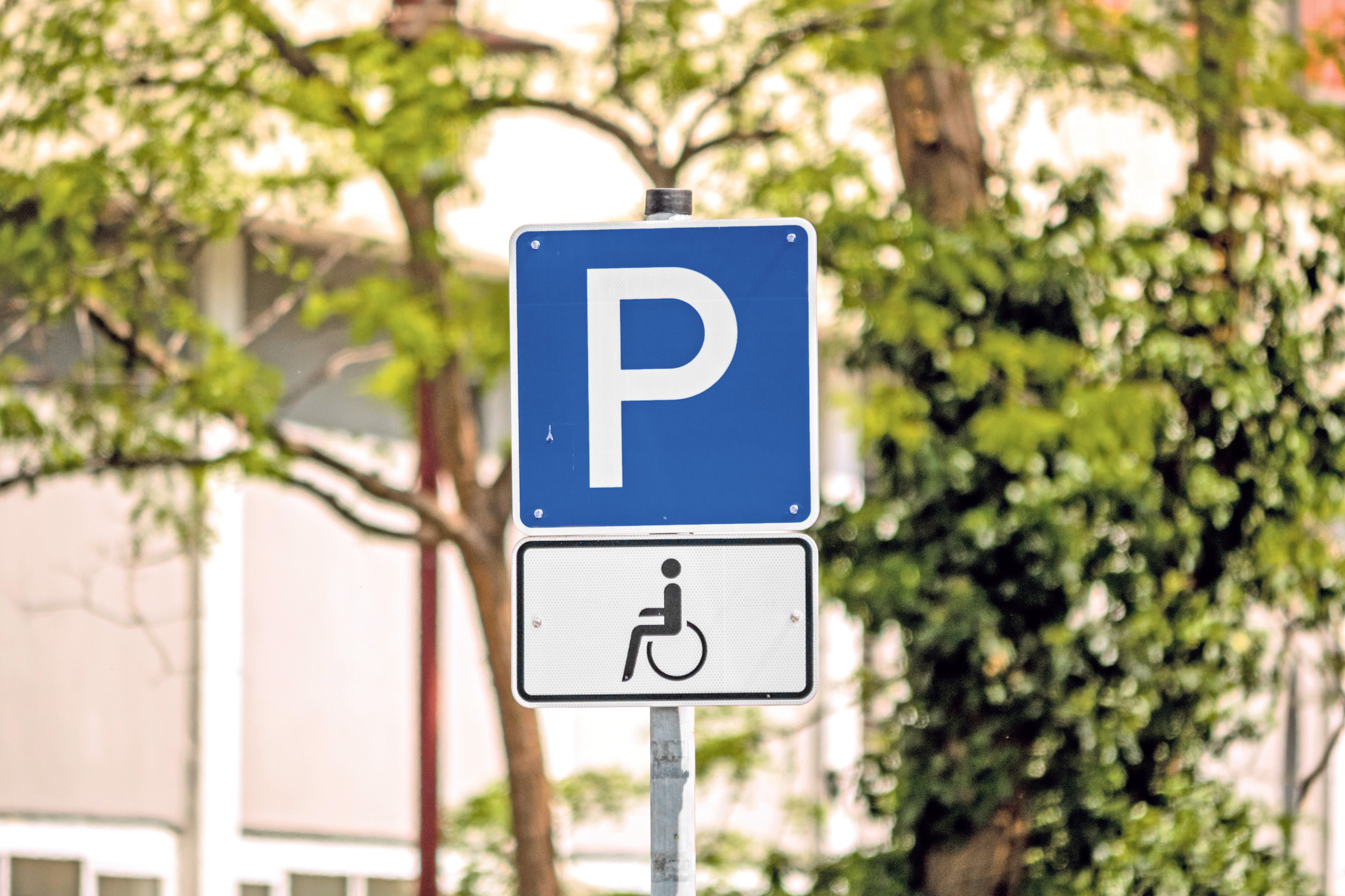Ein Verkehrsschild für einen Rollstuhlparkplatz vor einem Gebäude.