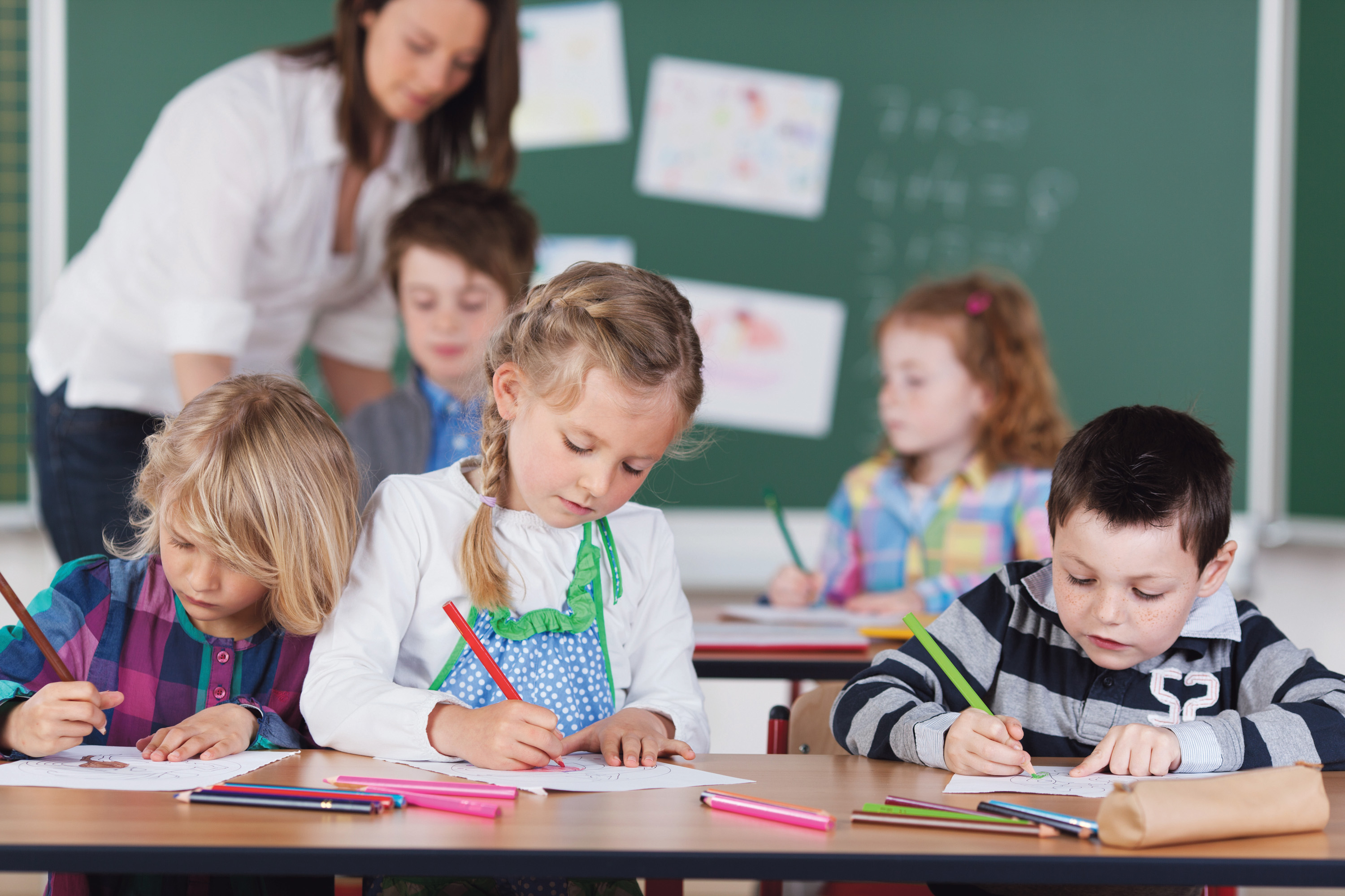 Mehr Geld für benachteiligte Kinder und Jugendliche Kinder einer Schulklasse bei Malen unter Anleitung einer Lehrerin.