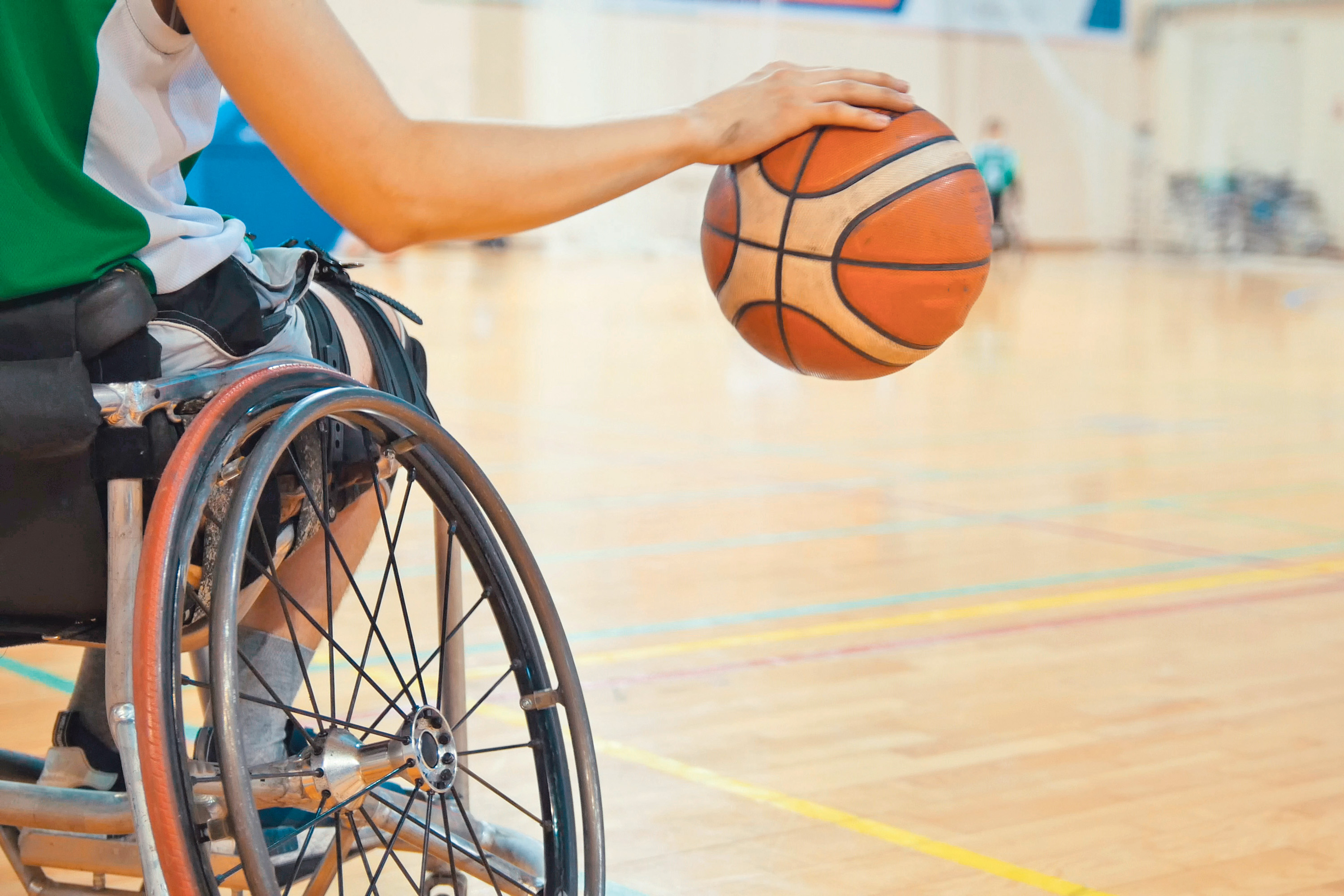 Neue Spielstätte für Behindertensport Ein Basketballspieler im Rollstuhl schlägt einen Ball.