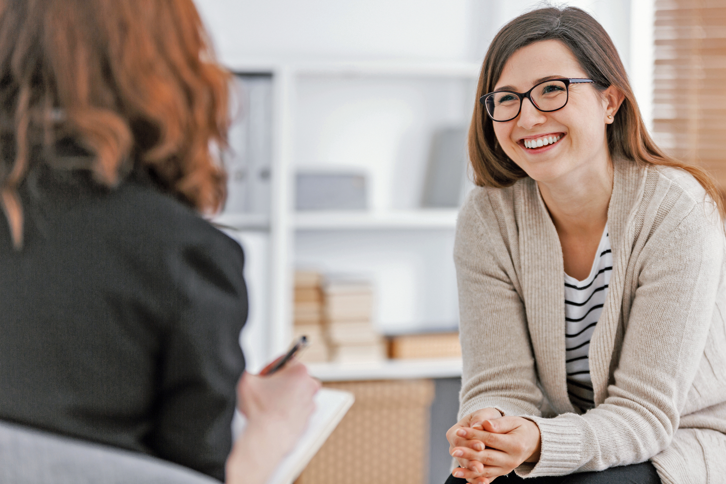 Steuertipp - Kosten für Psychotherapie absetzen Eine glückliche Frau während erfolgreicher Psychotherapie mit Therapeutin in der Klinik.