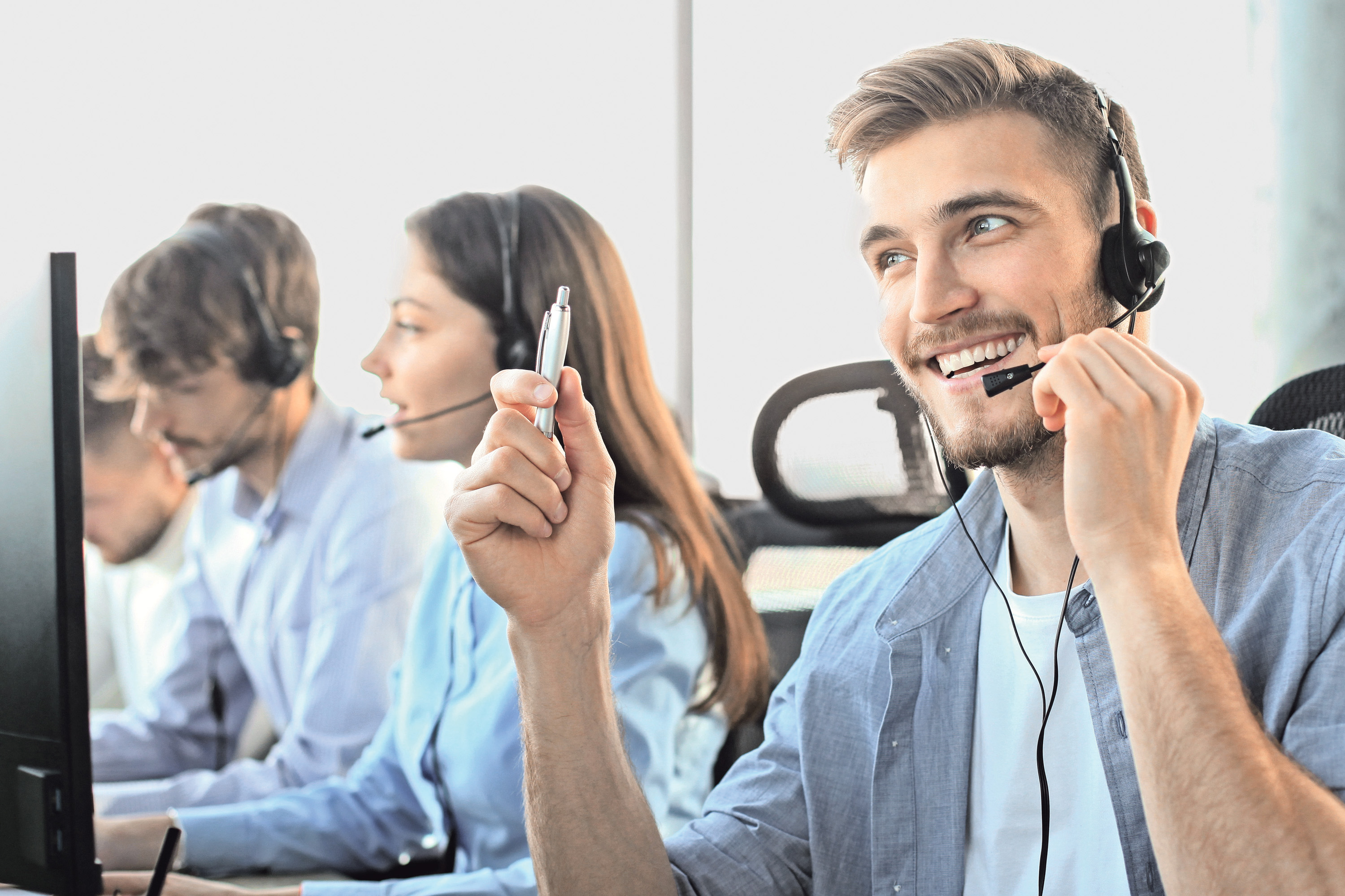 Servicetelefon für Grundsicherung und Sozialhilfe Porträt eines Callcenter-Teams mit gut gelaunten Kundendienstmitarbeitern bei der Arbeit.