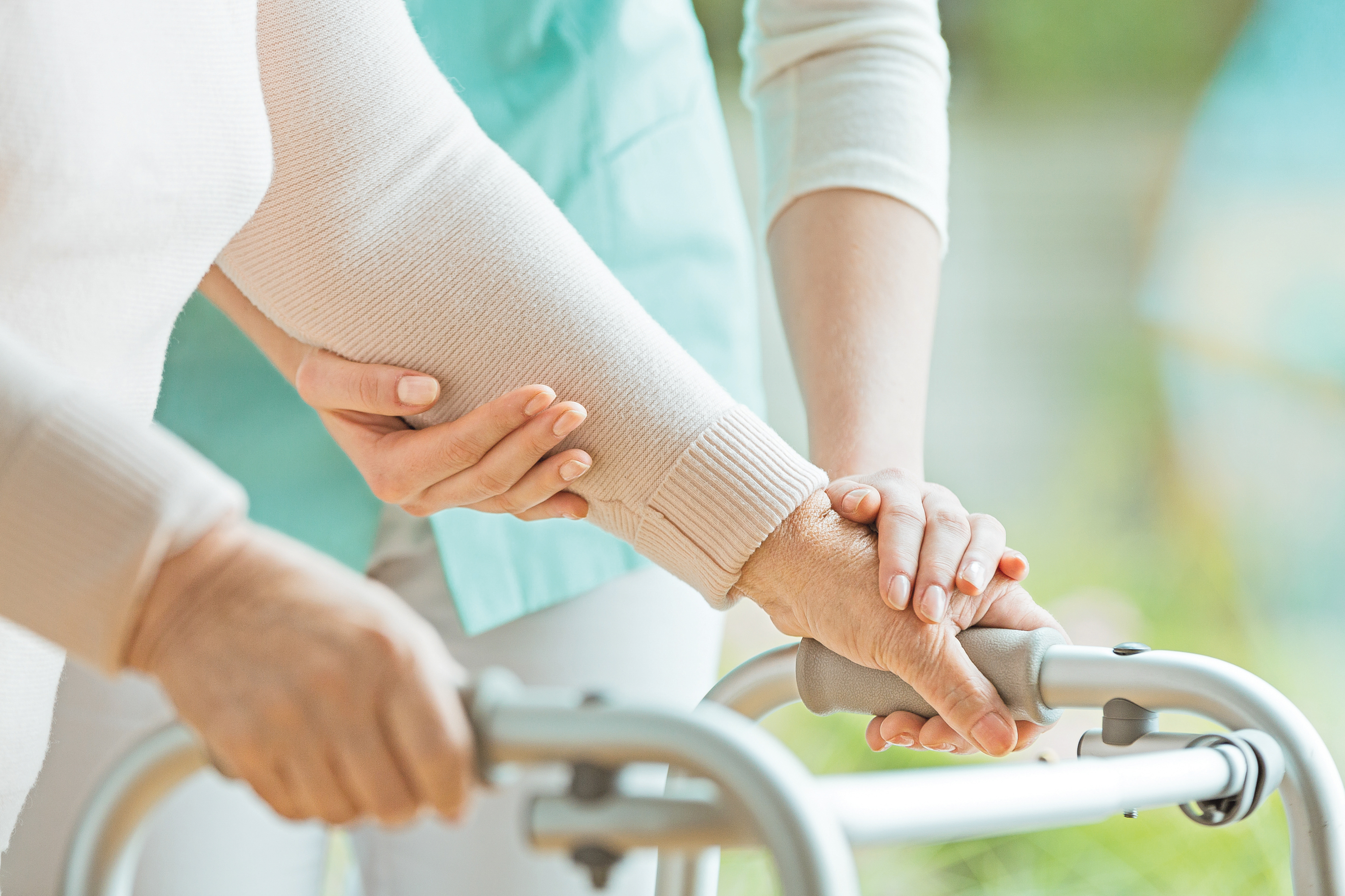 Eine &auml;ltere Dame h&auml;lt einen Rollator und eine Krankenschwesterunterst&uuml;tzt sie.