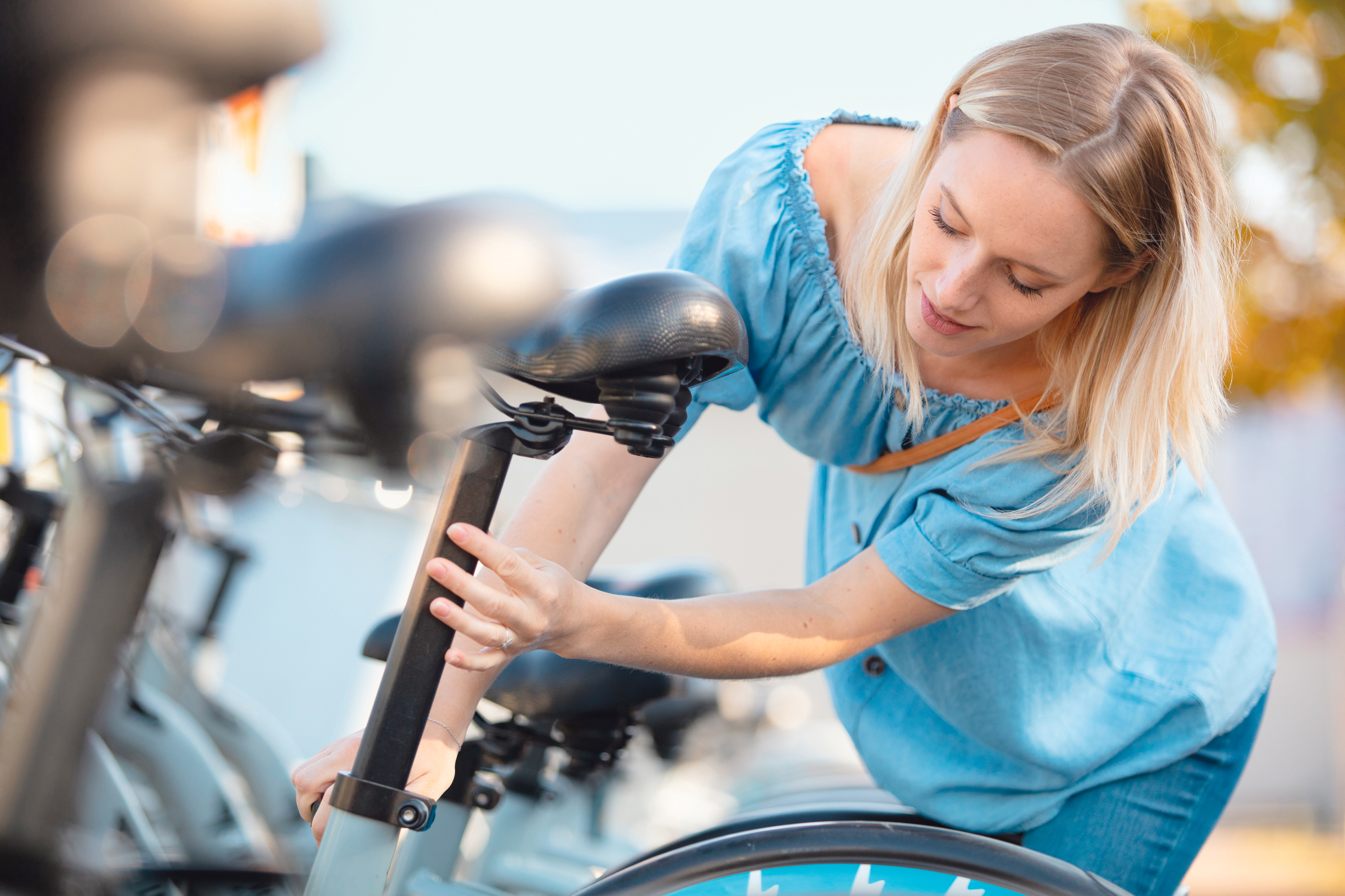 Rücken beim Fahrradfahren schonen Eine Radfahrerin stellt den Sattel am Fahrrad ein.
