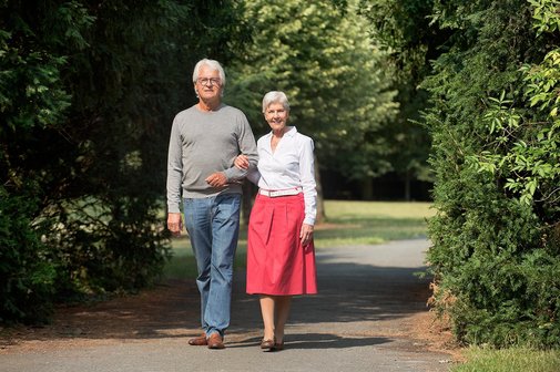 Seniorenpaar beim Spaziergang Ein älterer Mann und eine ältere Frau gehen gemeinsam spazieren im Park, sie halten sich an der Hand